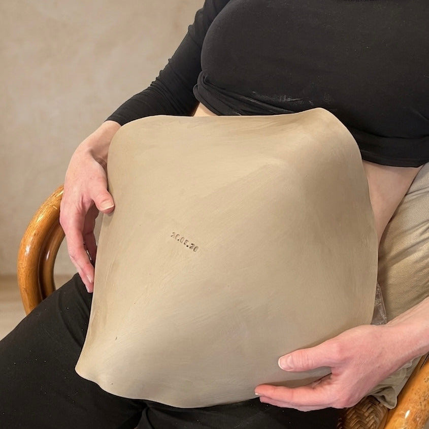 Frau hält ihre persönliche Belly Bowl, eine Babybauchschale aus Keramik mit eingestempeltem Datum als Erinnerung an die Schwangerschaft